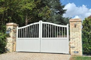 White wooden driveway gates installed between brick pillars
